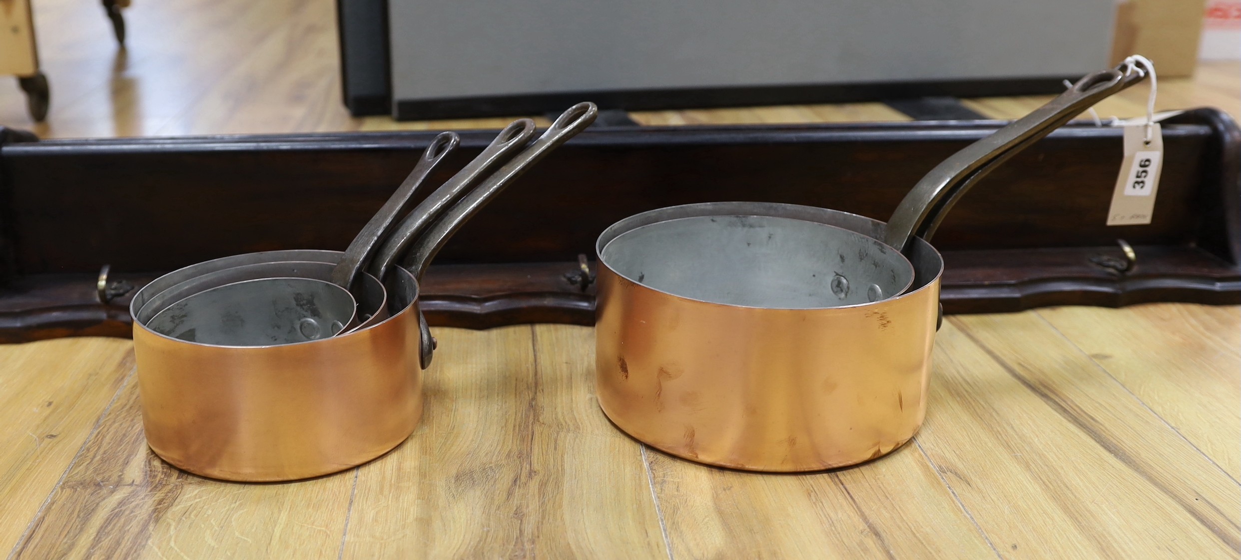A set of five French copper saucepans, pendant from rack, rack 103cms long